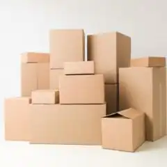 Corrugated-Packaging-2 Pile of brown cardboard moving boxes stacked against a white background, varying in size and shape.