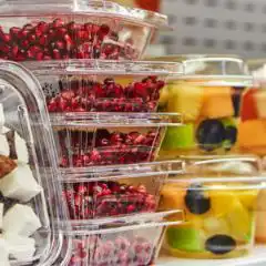 Food-Packaging Stack of clear plastic fruit cups filled with mixed berries and tropical fruit ready to eat.